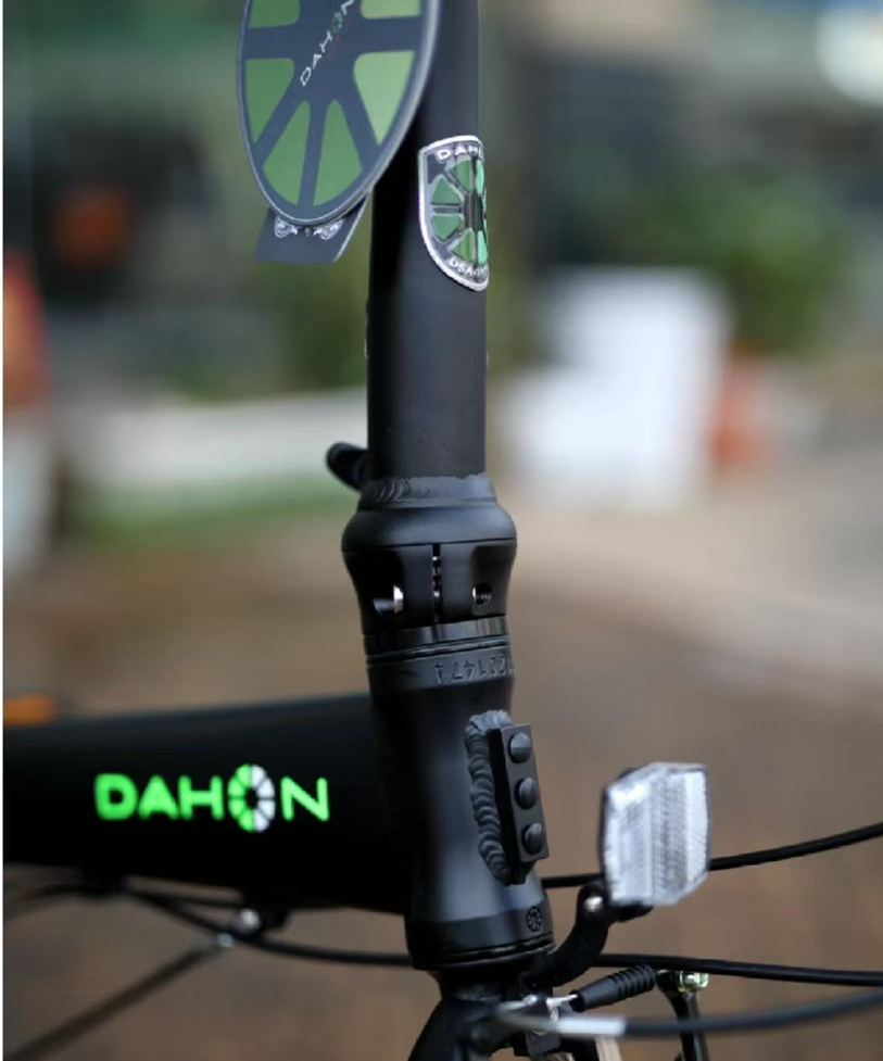 Close-up of a black DAHON folding bike's handlebar post and folding hinge, focusing on critical components.
