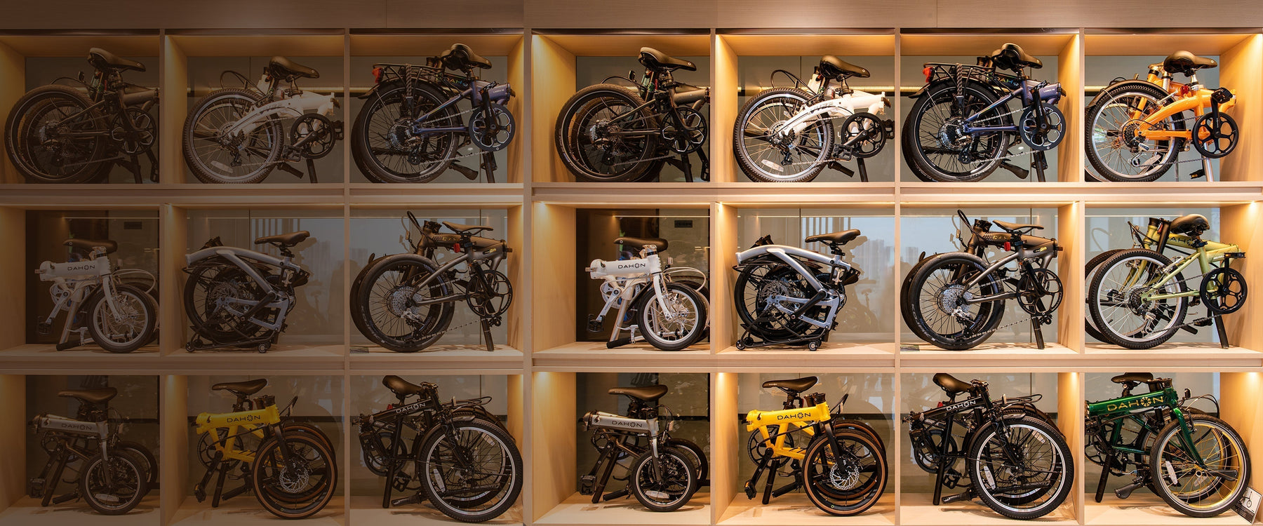 A display of DAHON folding bikes arranged in wooden shelves, showcasing various models and colors.