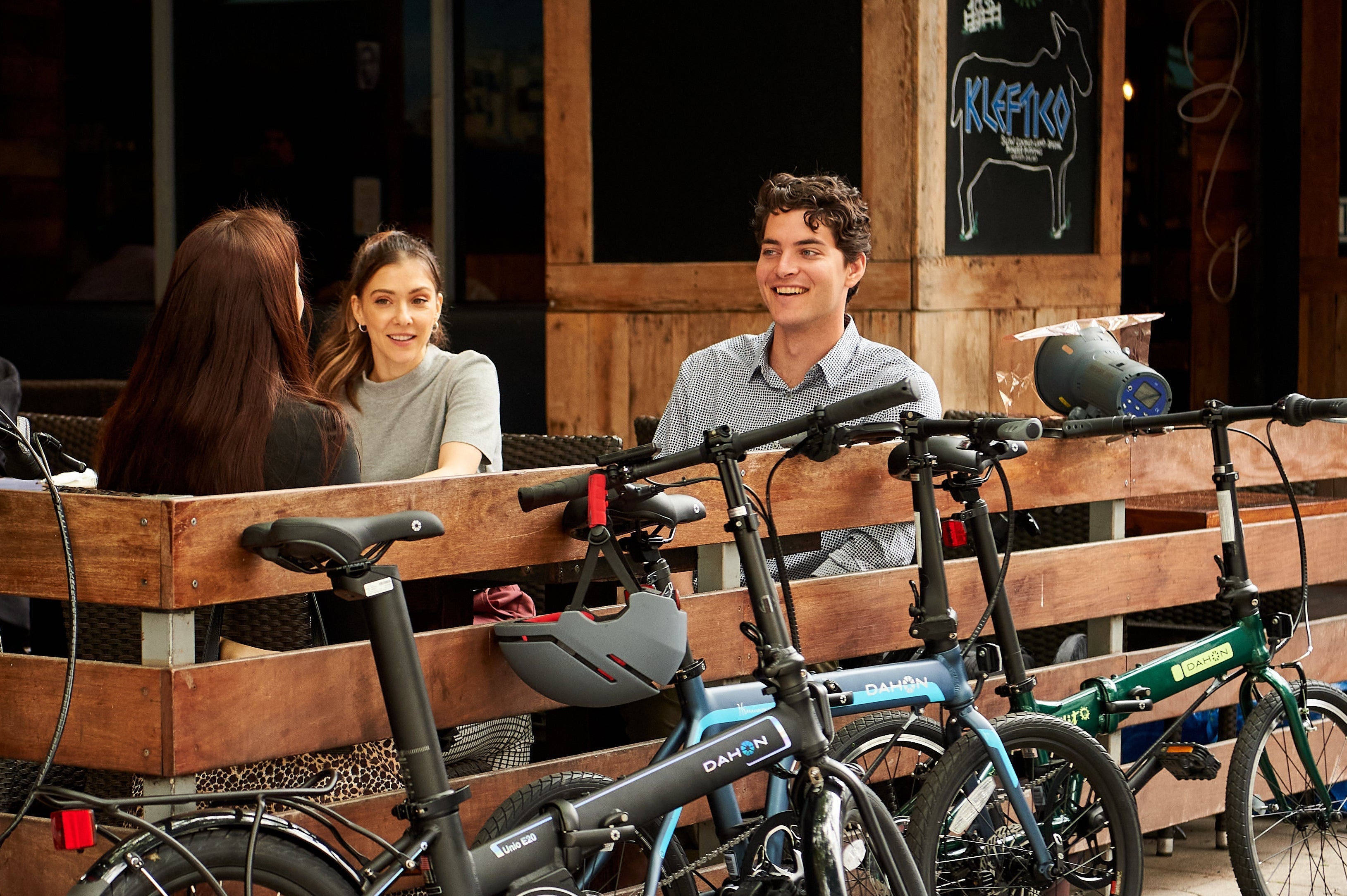 A group of friends sits on a city bench with their DAHON folding bikes parked beside them, ready for an urban adventure.