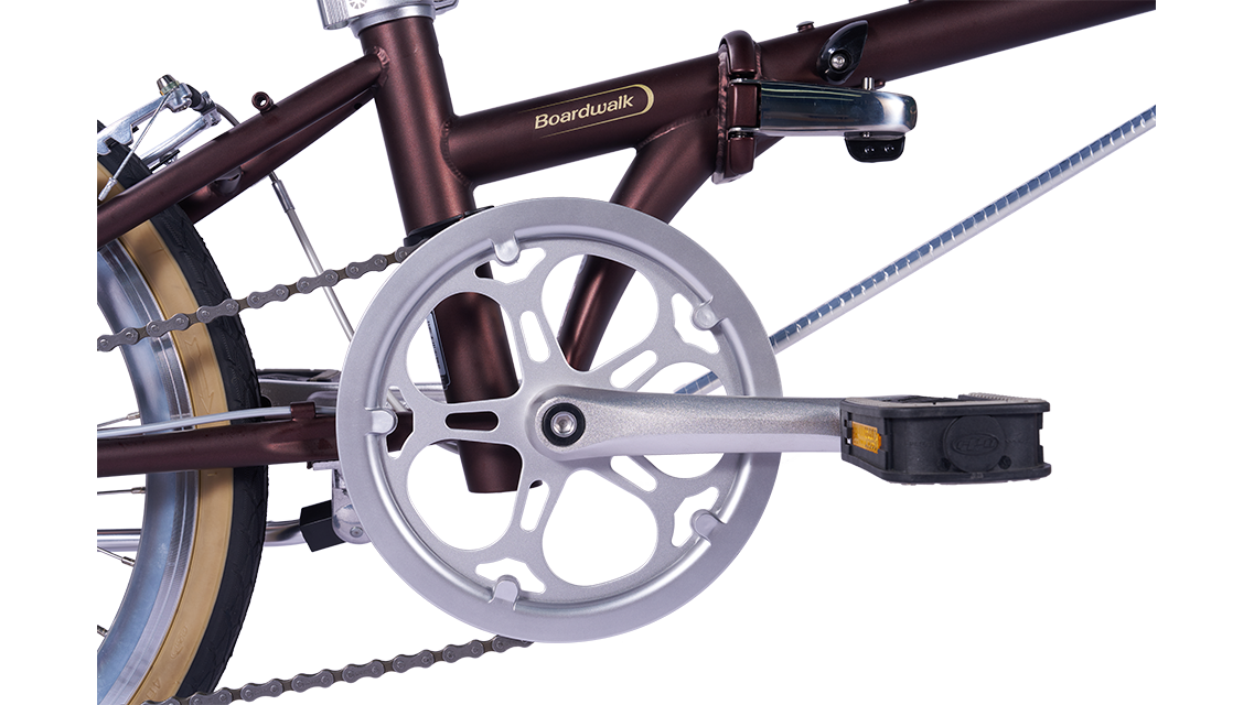 DAHON Boardwalk D7 folding bike featuring a metallic brown frame, silver crankset, chain, and pedals.