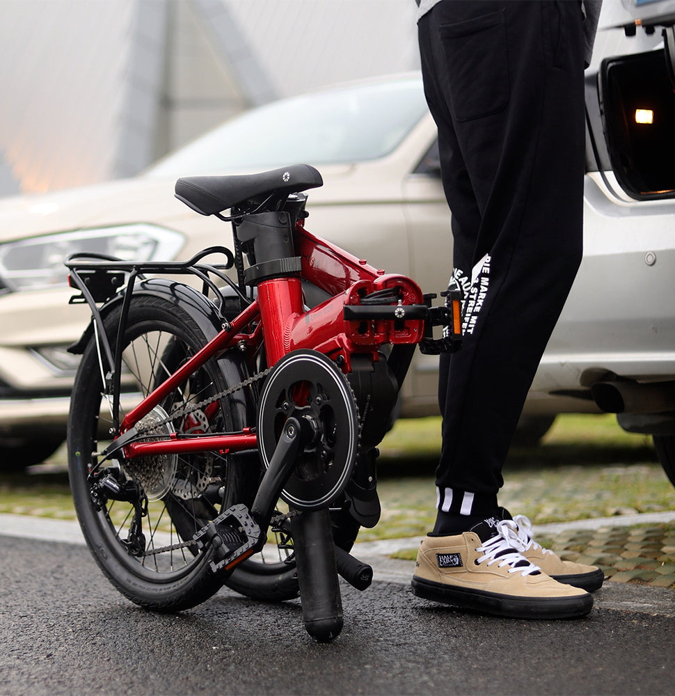 Red DAHON Unio E20 foldable electric bike partially folded, featuring mid-drive motor and rear rack for urban portability.