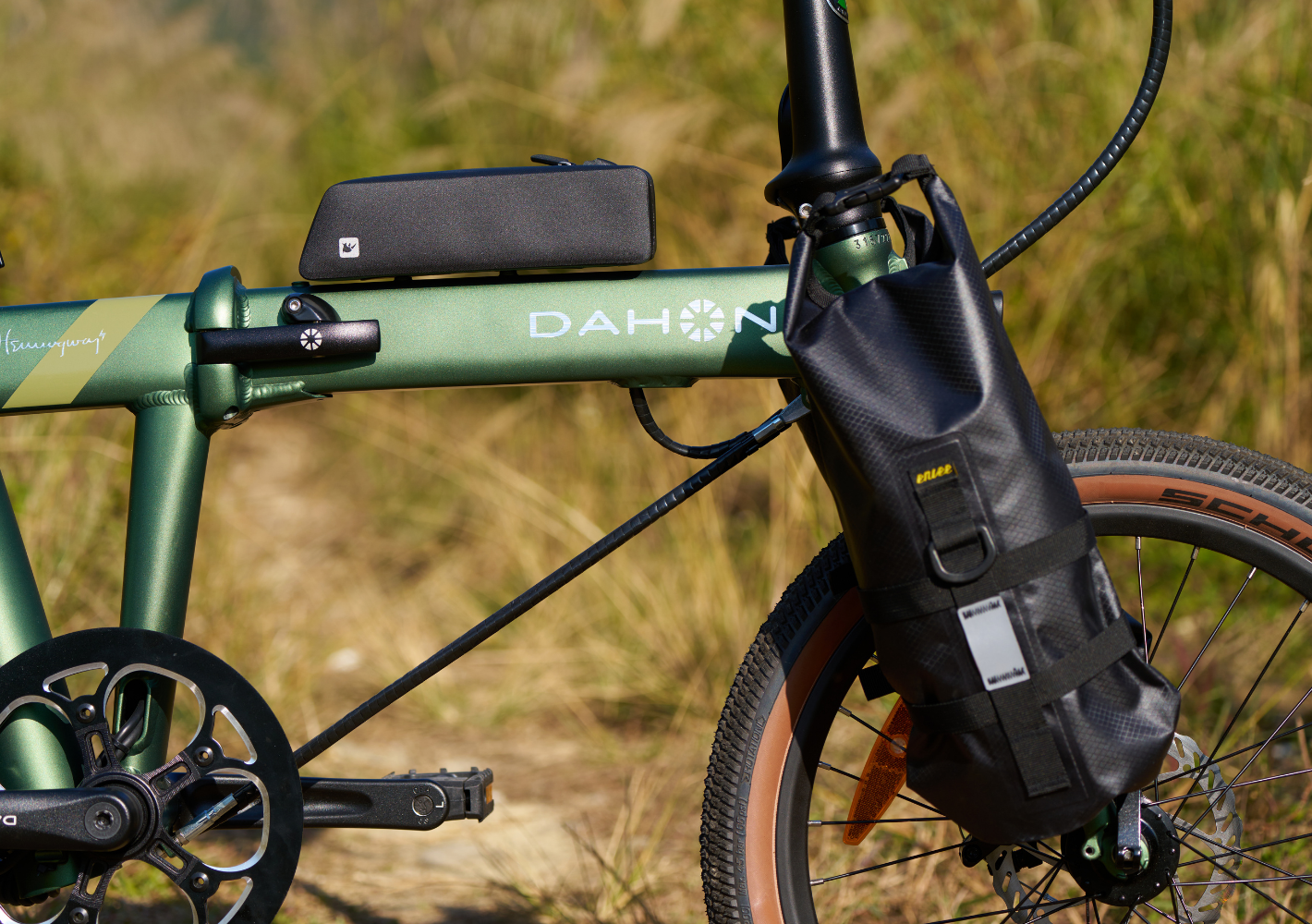 Green DAHON E-Hemingway foldable electric SUV bike frame details with black handlebar and frame bags, brown-rimmed tires.