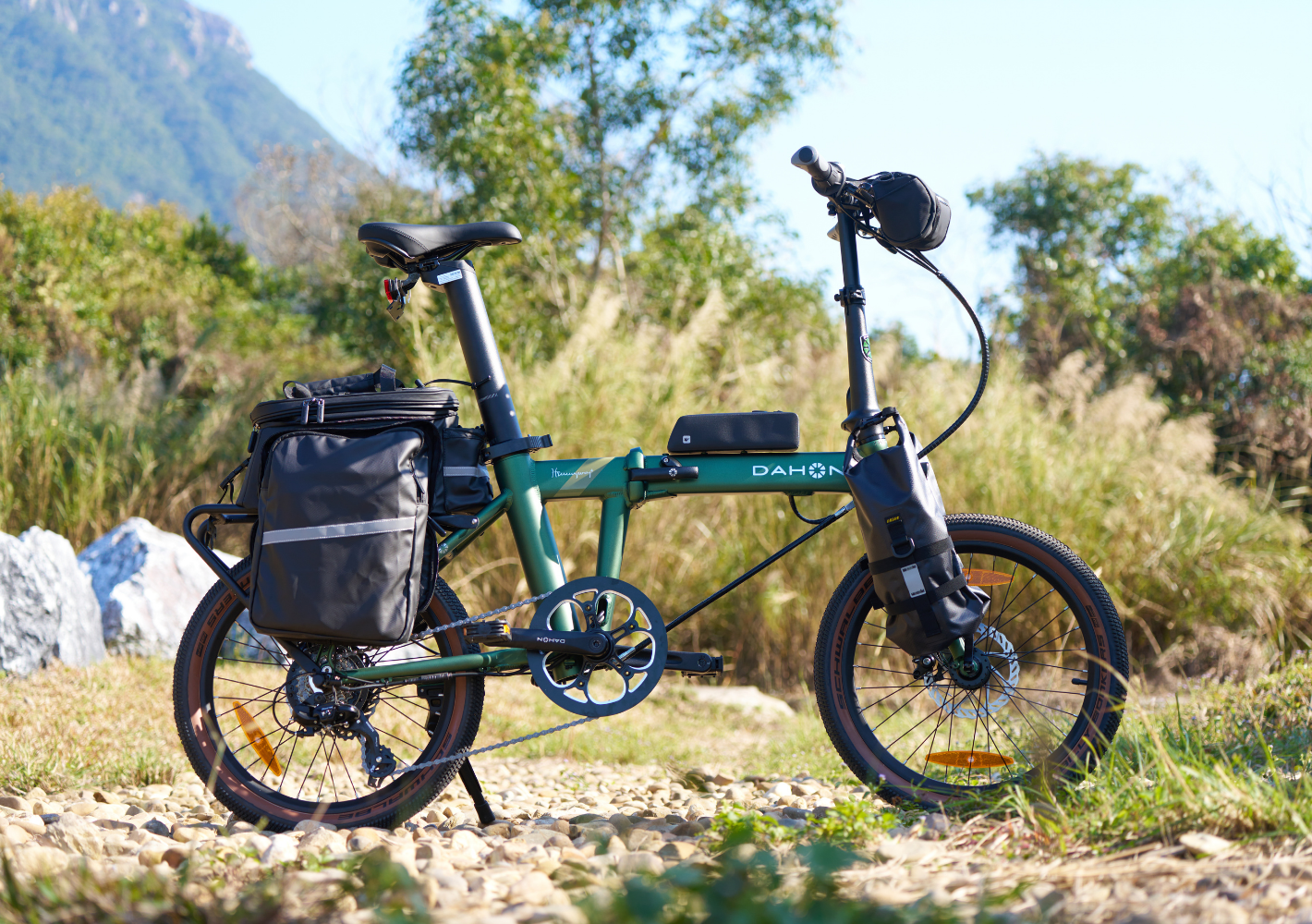 Deep green DAHON E-Hemingway foldable electric SUV bike with black seat, handlebar and rear bags, brown-rimmed tires.