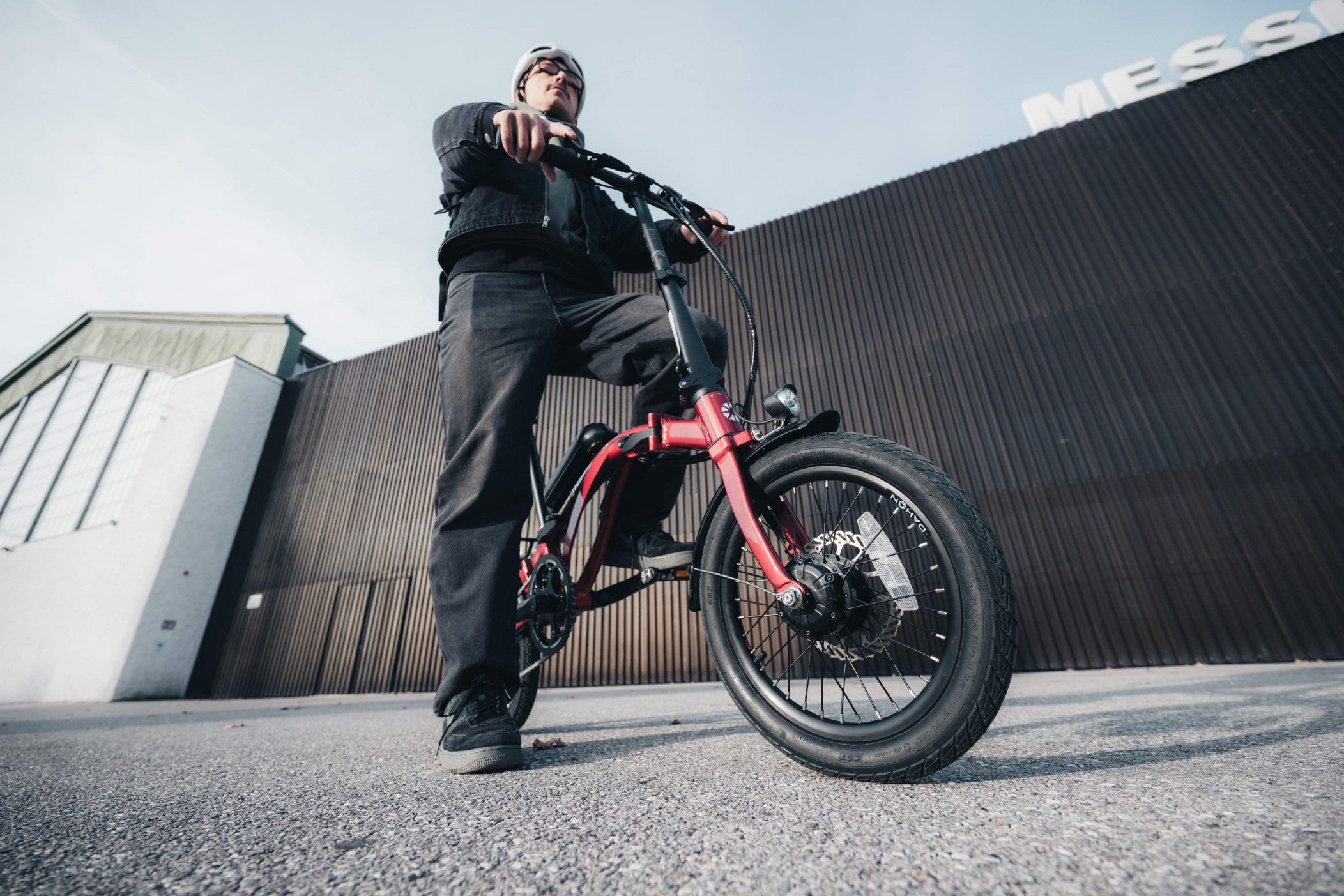 Rider on a red electric trifold bike with compact frame and fat tires in an urban setting