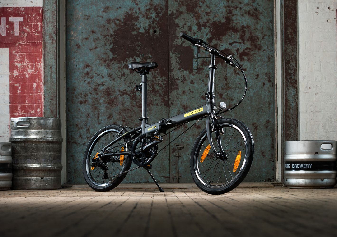 Black Dahon HIT D6 compact folding bike with yellow branding and orange reflectors.