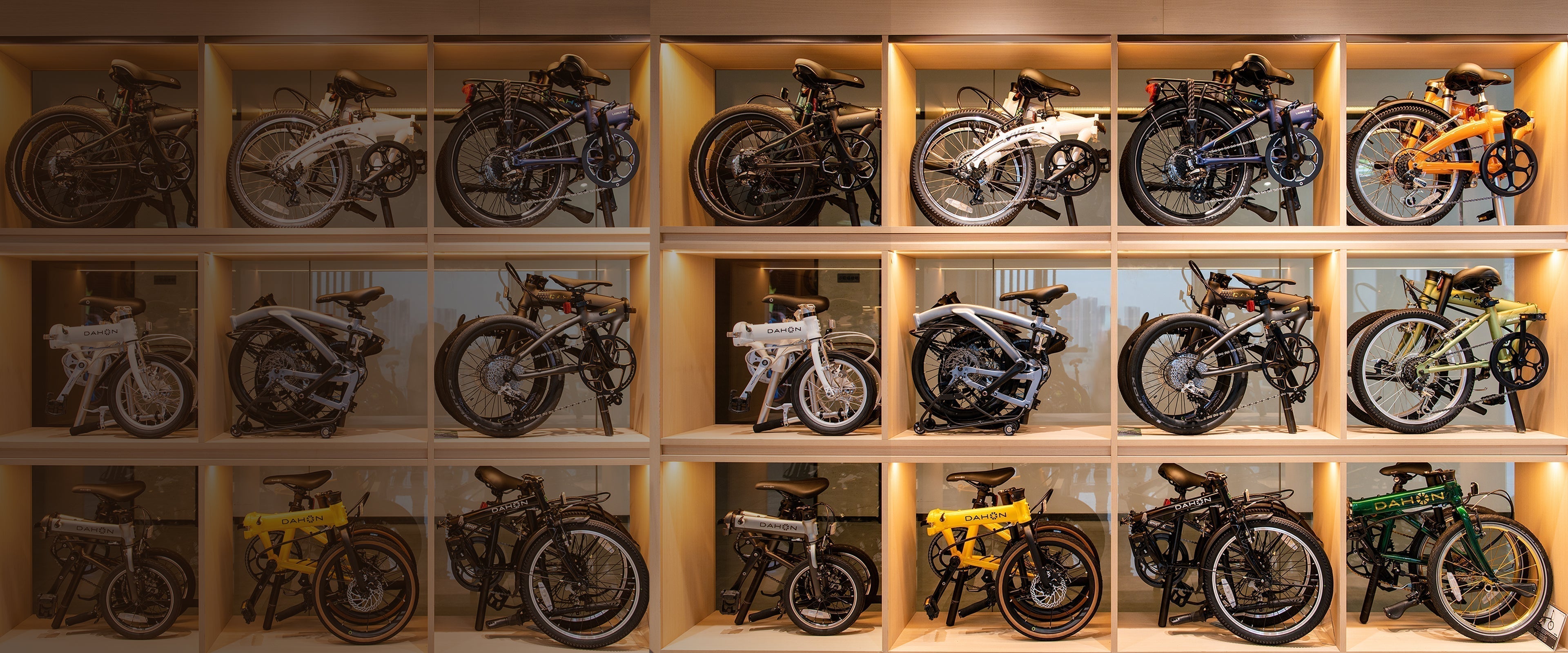 A display of DAHON folding bikes arranged in wooden shelves, showcasing various models and colors.