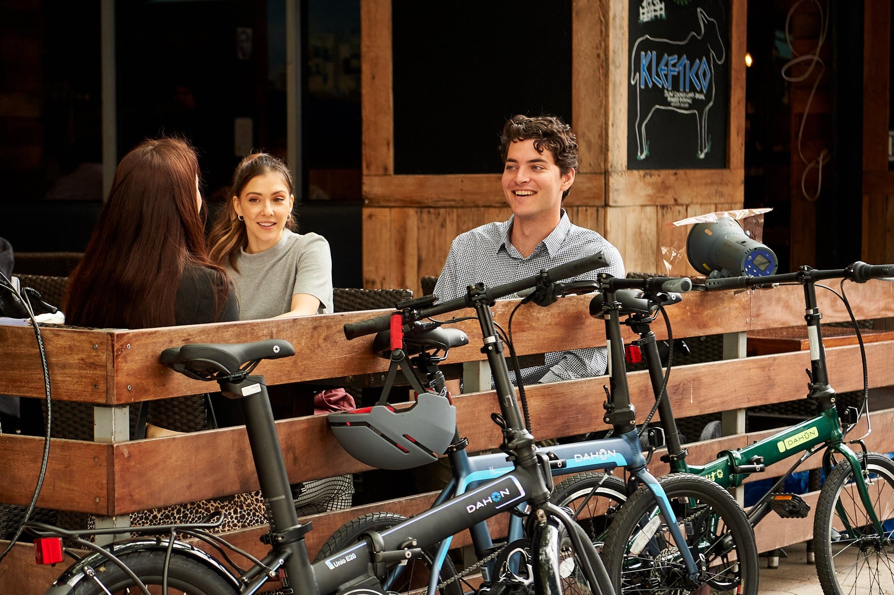 A group of friends sits on a city bench with their DAHON folding bikes parked beside them, ready for an urban adventure.